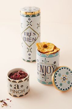 three tins filled with food sitting on top of a white table next to each other