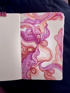 an open notebook with pink and purple swirls on the cover, sitting on a person's lap