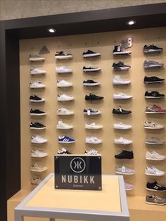 a display case filled with lots of white and black tennis shoes on top of shelves