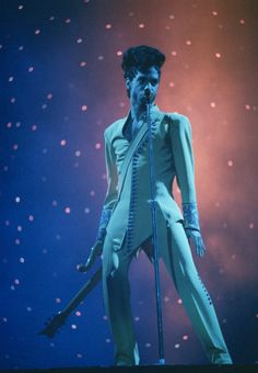 a male singer on stage with microphone and lights behind him