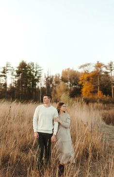 a man and woman standing in tall grass