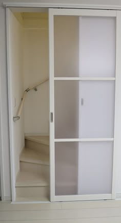 an open closet with white walls and shelves on the bottom floor, next to a stair case