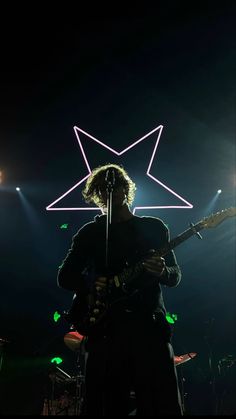 a man standing on top of a stage with a guitar in front of his face