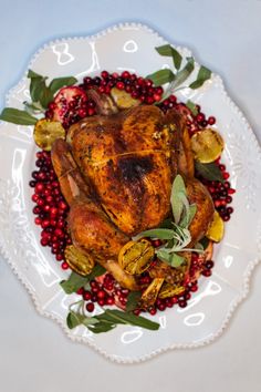 a white plate topped with a roasted turkey and cranberry garnishes