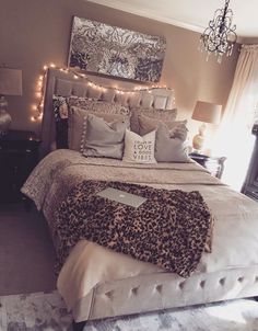 a bedroom with a bed, chandelier and pictures on the wall above it