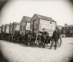 two men standing next to an old fashioned wagon