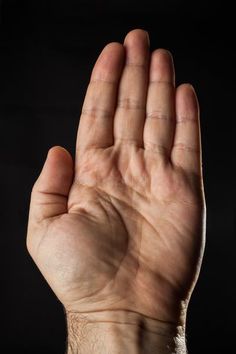 a person's hand with their palm up in the air, against a black background