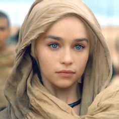 a woman with blue eyes is wearing a brown shawl and looking at the camera