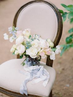 a bouquet of flowers is placed on the back of a chair with ribbon tied around it