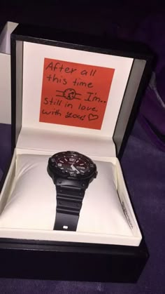 a black watch in a box with an orange note on the front and back side