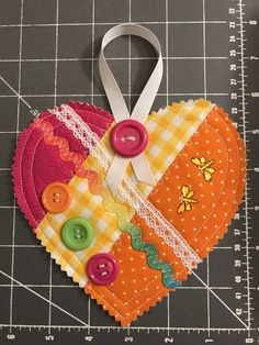 two heart shaped pieces of fabric with buttons attached to them on top of a cutting board