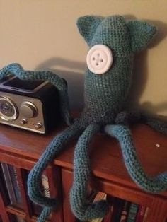 an octopus stuffed animal sitting on top of a book shelf next to a camera and stereo