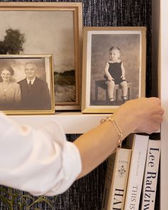 a woman holding a baby in her arms next to books and pictures on a shelf