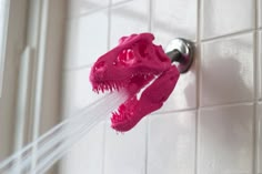 a pink toothbrush being held up to the side of a white tiled wall