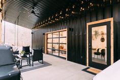 an outdoor living area with black furniture and lights on the ceiling, along with large sliding glass doors