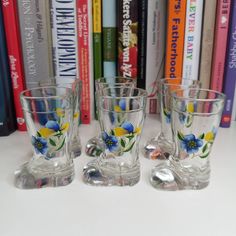 three glass cups sitting next to each other on a table with books in the background