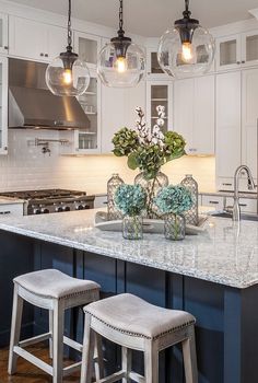 a kitchen island with two vases and flowers on it in front of an oven