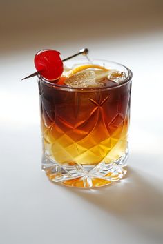 a close up of a drink in a glass with a cherry on the top and ice