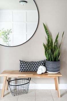 a wooden table topped with a potted plant next to a mirror