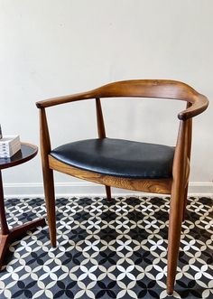 a wooden chair sitting on top of a black and white floor next to a table