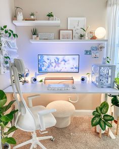 a white desk topped with a computer monitor next to a chair and potted plants