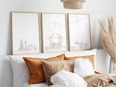 three framed nativity images hang on the wall above a bed with pillows and blankets