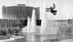 a man flying through the air while riding a dirt bike in front of a fountain