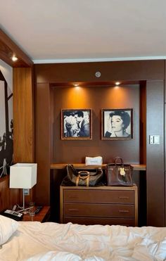 a bedroom with two pictures on the wall and a dresser in front of it,