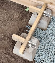 a wooden cross sitting on top of a pile of rocks next to a building with nails stuck in it