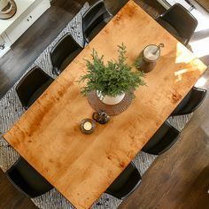 a wooden table with chairs around it and a potted plant on the centerpiece