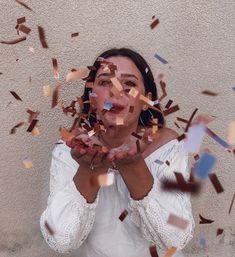 a woman standing in front of a wall with confetti all over her face