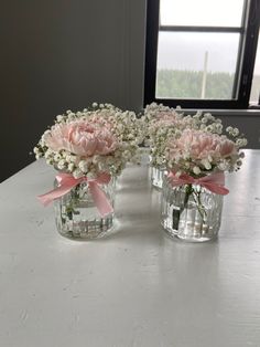 two clear vases with pink flowers and baby's breath are on a table