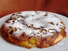 a white plate topped with a pastry covered in powdered sugar on top of a table