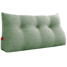 a green pillow with buttons on the front and back side, sitting against a white background