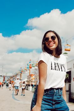 a woman standing in the middle of a street with her hand on her hip and smiling