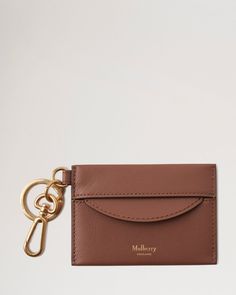 a brown leather card case with a gold keychain hanging from it's side