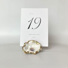 a white and gold brooch sitting on top of a table next to a card