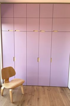 a wooden chair sitting in front of purple cupboards