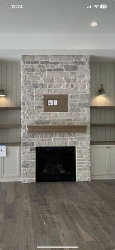 an empty living room with a fireplace and built in shelving units on either side