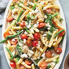 a white plate topped with pasta and veggies covered in fettuccine