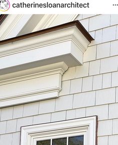 a cat sitting on the ledge of a window sill in front of a house