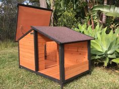 a small dog house in the grass with its door open