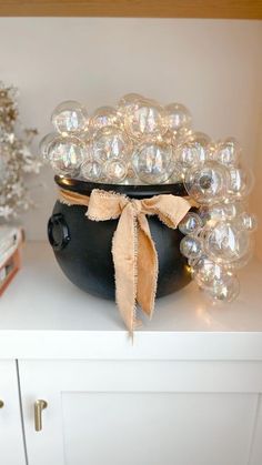 a black pot sitting on top of a white shelf filled with glass balls and ornaments