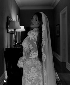 a woman in a wedding dress and veil is looking at the camera while standing in a hallway