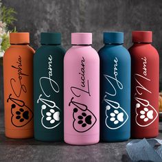 four different colored water bottles with writing on the side and paw prints on the sides