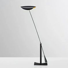 a floor lamp that is on top of a white table and has a black base