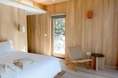 a white bed sitting in a bedroom next to a wooden wall with sliding glass doors