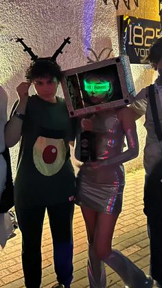 three people dressed up in costumes standing next to each other and holding an electronic device