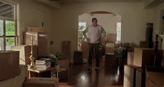 a man is standing in the middle of a room filled with boxes and moving furniture