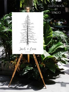 an easel with a drawing of a pine tree on it in front of some plants